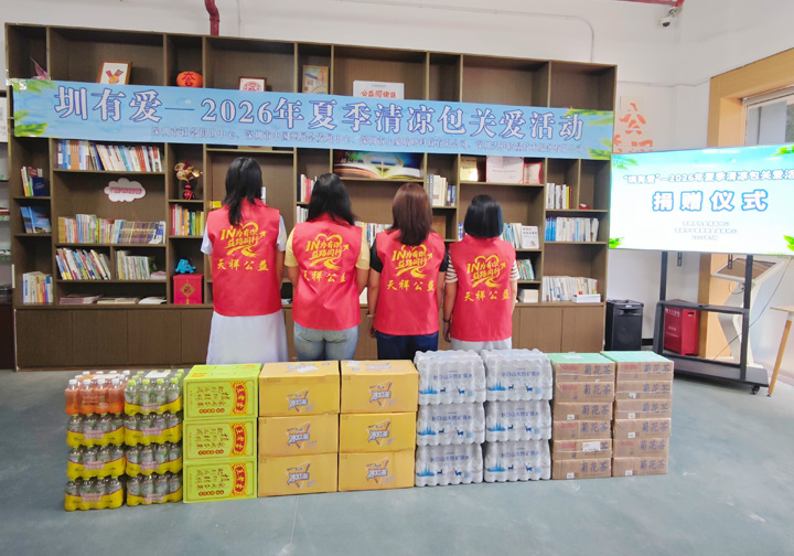 Intertek colleagues in branded clothing stand with their backs to donated items. 