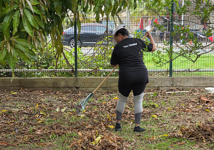 Intertek colleague doing some raking in a "Team Trinidad" t-shirt. 