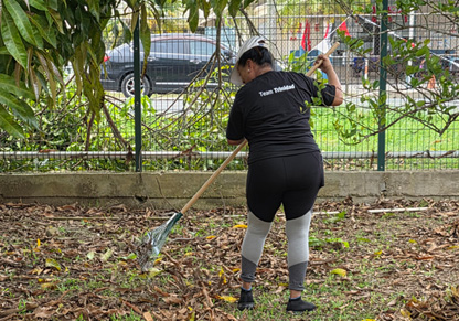 Intertek colleague doing some raking in a "Team Trinidad" t-shirt. 
