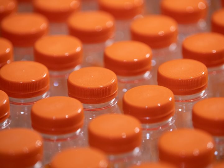 an expanse of transparent plastic bottles with orange lids